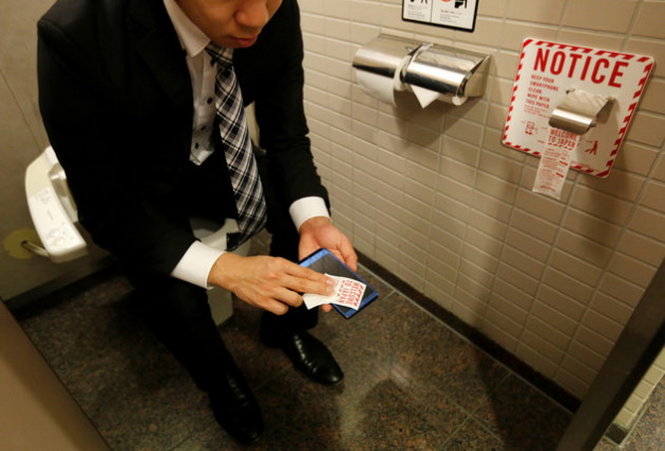 Một người đàn ông đang thử dùng giấy vệ sinh cho điện thoại ở sân bay Narita - Ảnh: REUTERS