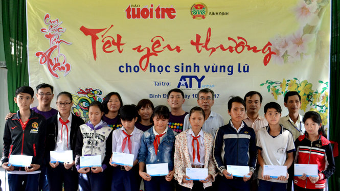 Đại diện ban tổ chức và nhà tài trợ chụp ảnh lưu niệm với các học sinh P.Bình Định (thị xã An Nhơn) được nhận quà của chương trình “Tết yêu thương cho học sinh vùng lũ” - Ảnh: DUY THANH