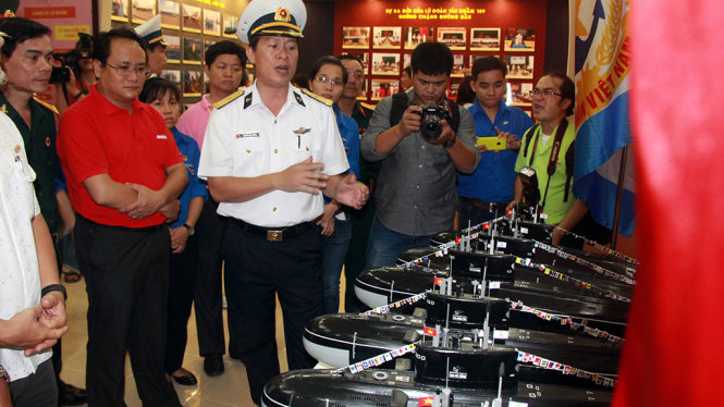 Thiếu tá Nguyễn Hoàng  Dương - phó chính ủy Lữ đoàn 189 giới thiệu mô hình sáu tàu ngầm mang tên sáu tỉnh thành cho lãnh đạo, đoàn viên trong đoàn công tác - Ảnh: TRUNG TÂN