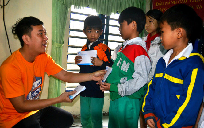 Ông Nguyễn Hoàng Minh Tân - giám đốc đối ngoại và marketing của ATY trao quà cho học sinh vùng lũ - Ảnh: LÊ TRUNG
