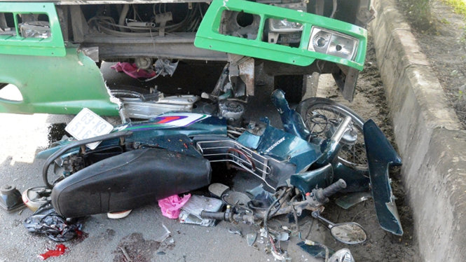 Chiếc xe máy bị kẹt cứng dưới gầm trước xe buýt, hư hỏng nặng sau vụ tai nạn - Ảnh: Lê Phan