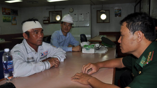 Ngư dân Huỳnh Tấn Thành với vết băng trên đầu đang ngồi trên tàu PTSC Thái Bình - Ảnh: Đông Hà.