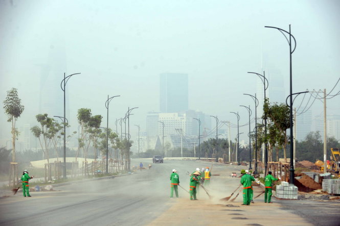 Công nhân vệ sinh lờ mờ trong sương phía sau là trung tâm thành phố mờ ảo - Ảnh: HỮU KHOA