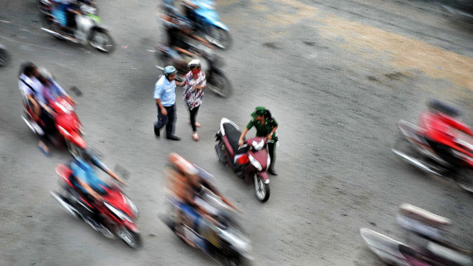Người đàn ông cùng với nữ thanh niên xung phong dìu người phụ nữ và dẫn xe máy vào lề đường  - Ảnh: HỮU KHOA