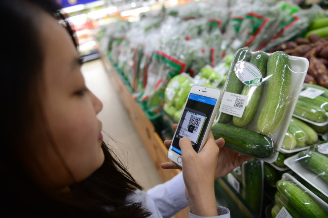 Một khách hàng dùng điện thoại để truy xuất nguồn gốc rau khi mua tại siêu thị Co.opMart Rạch Miễu, Q. Phú Nhuận, TP.HCM sáng 18-1 - Ảnh: QUANG ĐỊNH