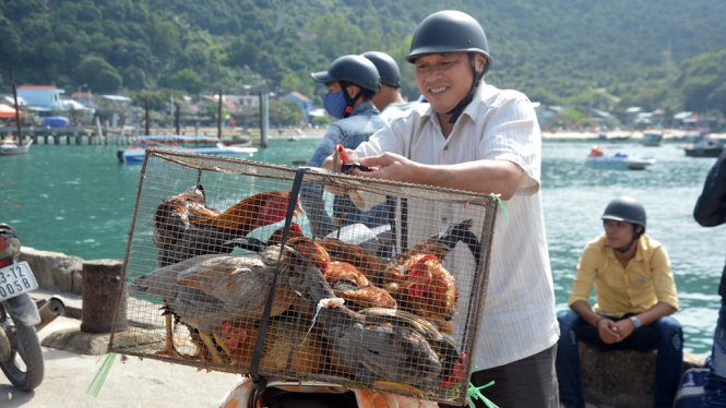 Người đàn ông buôn gà trên đảo hồ hởi nhận hàng từ ngoài đất liền gửi ra - Ảnh: THANH BA