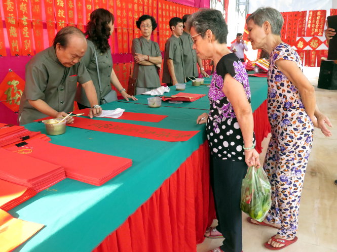 Bà Trần Tú Vân (thứ 2 từ phải) đang đặt nhà thư pháp Trương Lộ viết câu liễn - Ảnh: L.Điền
