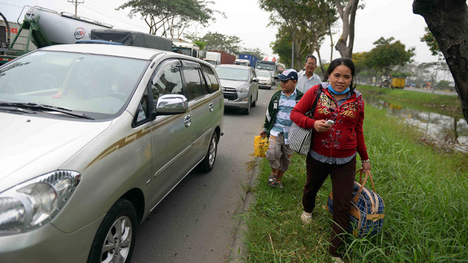 Người dân đi xe đò về quê ăn tết phải xuống xe đi bộ trên đường Nguyễn Văn Linh vì kẹt xe kéo dài - Ảnh: HỮU KHOA
