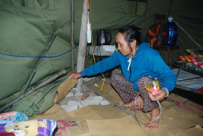 Bà Phạm Thị Dần và con trai cả tá túc trong túp lều bạt nhựa được phát từ sau ngày lũ tràn vào - Ảnh: BÁ DŨNG