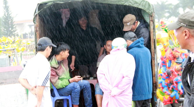 Trời mưa to, người mua vắng vẻ nên các chủ vườn túm tụm ngồi cà phê - Ảnh: Đoàn Cường