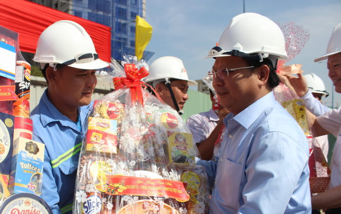 Phó bí thư thường trực Thành ủy TP Tất Thành Cang tặng quà, thăm hỏi công nhân sáng mùng 1 Tết. Ảnh: Mai Hoa