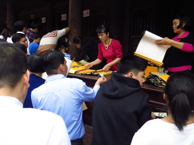 Đến 11 giờ, do số người xin chữ quá đông, giấy lụa đỏ tạm thời hết, nên nhiều người dù muốn xin chữ trên lụa đỏ lại đành phải xin chữ trên nền giấy lụa màu vàng - Ảnh NGỌC HÀ