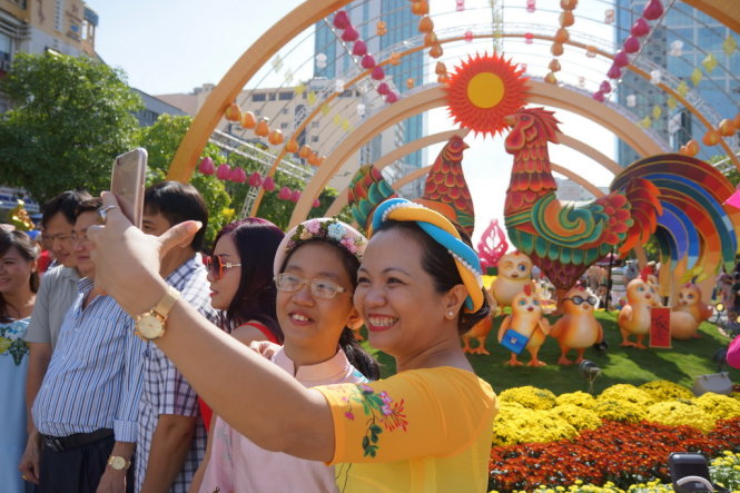 Chụp ảnh kỷ niệm với đường hoa Tết Đinh Dậu 2017 trên phố đi bộ Nguyễn Huệ, Q.1, TP.HCM - Ảnh: Nguyễn Công Thành