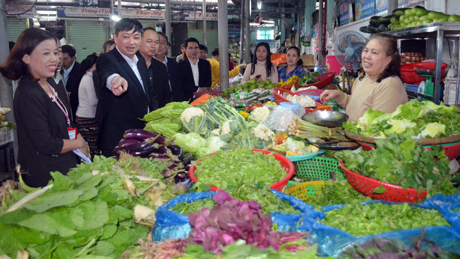 Ông Đặng Việt Dũng hỏi thăm nguồn gốc rau củ tại chợ Đống Đa - Ảnh: TẤN LỰC