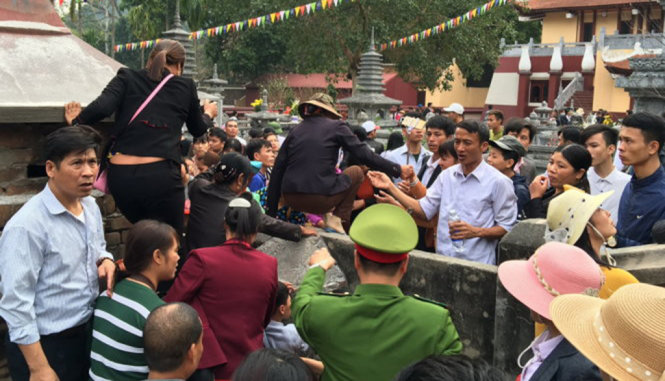 Nhiều du khách bất chấp việc ngăn cản của lực lượng chức năng vẫn trèo tường giành đường vào chùa trước khi cử hành lễ khai hội - Ảnh: XUÂN LONG