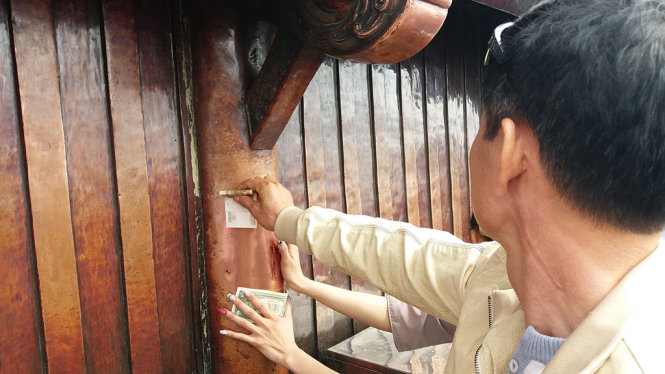 Nhiều người dùng cả tiền nước ngoài cọ vào chùa Đồng lấy may - Ảnh: ĐỨC HIẾU