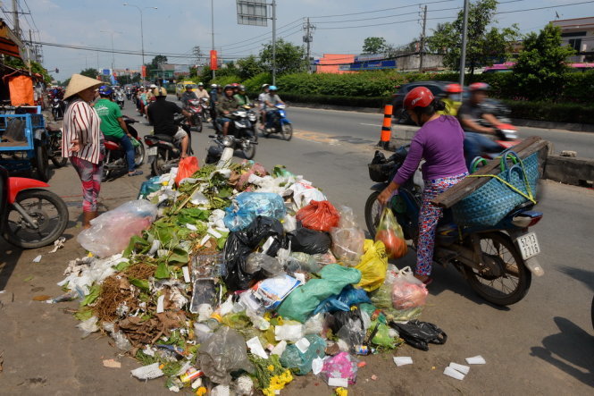 Một phụ nữ góp phần làm đầy thêm đống rác trên quốc lộ 22, huyện Hóc Môn, TP.HCM trưa 4-2 - Ảnh: HỮU KHOA