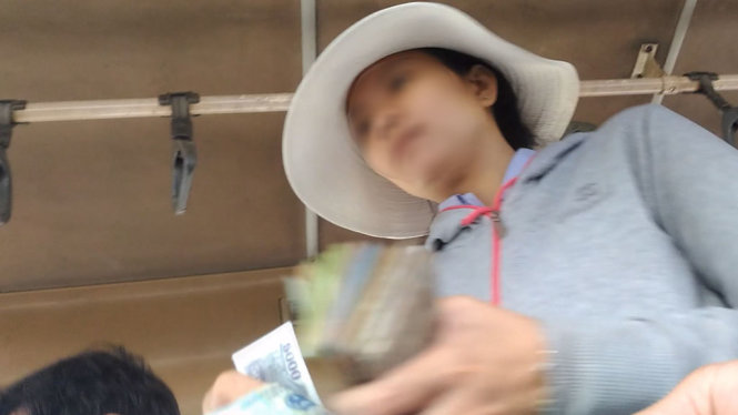 Nữ nhân viên của Xe 53N5646 đang thu 25.000 đồng/khách từ Suối Tiên (Q9) tới bến xe miền Tây (giá đúng là 15.000 đồng) mà không đưa vé theo quy định. Trước đó, nhân viên này đã thu 40.000 đồng cho đoạn đường có giá đúng là 10.000 đồng - Ảnh: Cắt từ video clip