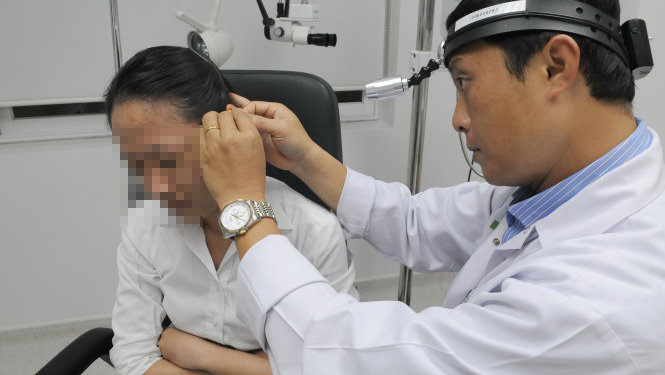 Bác sĩ khoa tai mũi họng ở một bệnh viện khám tai cho một bệnh nhân - Ảnh: MINH ĐỨC