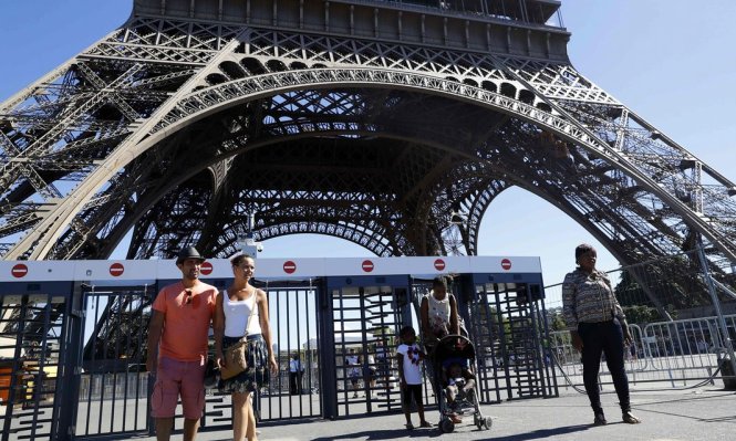 Du khách chụp ảnh tại tháp Eiffel. Trong tương lai, lớp rào 'thiếu trang nhã' ở chân tháp sẽ được thay bằng kính chống đạn - Ảnh: AFP/Getty Images