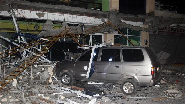 Ô tô bị mắc kẹt trong đống gạch, sắt của một tòa nhà bị hư hại do động đất - Ảnh: Reuters