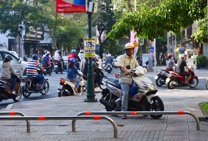 Một người theo thói quen chạy xe lên vỉa hè, nhưng đã bối rối khi bị ngăn lại bởi các barie vừa được lắp đặt (ảnh chụp ở vỉa hè đường Nguyễn Bỉnh Khiêm, Q.1, TP.HCM) - Ảnh: Duyên Phan