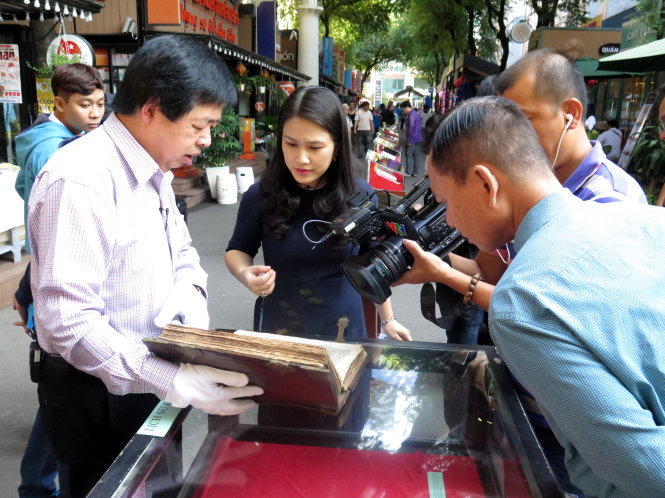Ông Dư Thanh Khiêm (trái) đang giới thiệu quyển Kinh Thánh đầu tiên của Hà Lan đang trưng bày tại Đường sách TPHCM - Ảnh: L.Điền