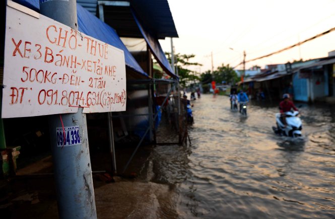Biển báo dịch vụ chở thuê xe qua đoạn ngập nước trên đường Lê Văn Lương - Ảnh: HỮU KHOA