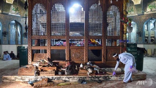 Một nhân viên điều tra thu thập chứng cứ ở hiện trường vụ đánh bom tự sát trong đền thờ thánh Lal Shahbaz Qalandar - Ảnh: AFP