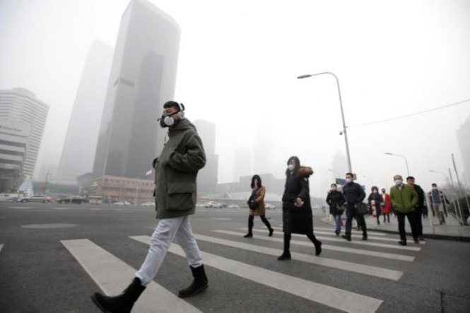 Một người đàn ông bịt khẩu trang đi qua một tòa nhà văn phòng trong tình trạng ô nhiễm không khí đã được cảnh báo ở mức báo động đỏ tại Bắc Kinh, Trung Quốc ngày 21-12-2016 - Ảnh: Reuters