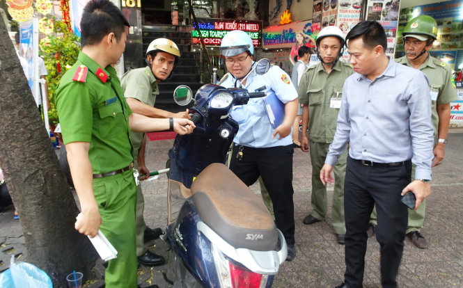Lực lượng chức năng tạm giữ một xe máy không người nhận đậu trên vỉa hè đường Phạm Ngũ Lão - Ảnh: Lê Phan