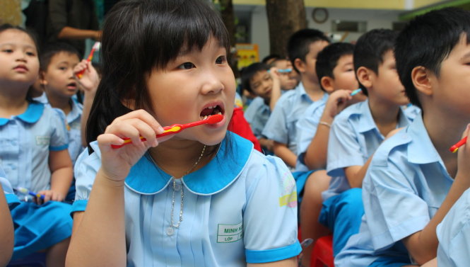 Các em học sinh thích thú thực hành chải răng theo hướng dẫn của cô giáo - Ảnh Phương Nguyễn