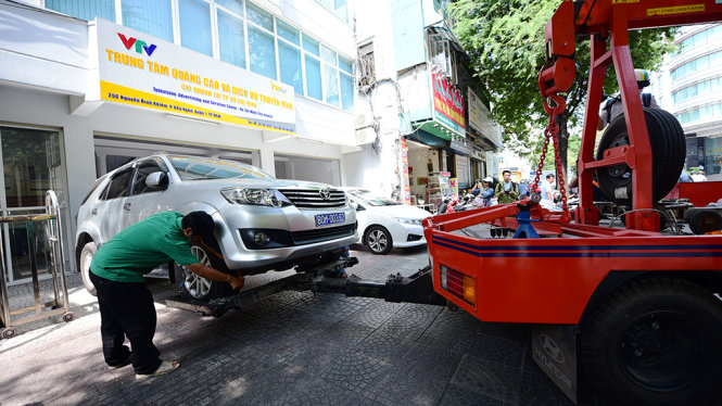 Đội kiểm tra xử phạt vỉa hè, lòng đường quận 1 cẩu xe biển xanh vi phạm vỉa hè trước tòa nhà trụ sở của VTV tại TP.HCM trên đường Nguyễn Bình Khiêm, Q.1 - Ảnh: HỮU THUẬN