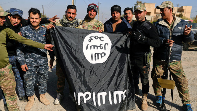 Binh lính Iraq chụp hình với lá cờ của IS bỏ lại sau khi chiếm được sân bay tại thành phố Mosul - Ảnh: Reuters