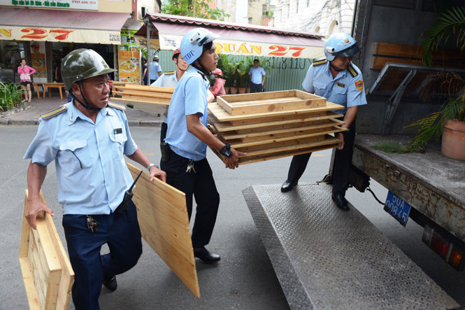 Lực lượng Quản lý trật tự đô thị thu giữ bàn ghế của một quán ăn bày trên vỉa hè đường Nguyễn Trung Trực (Q.1, TP.HCM) - Ảnh: LÊ PHAN