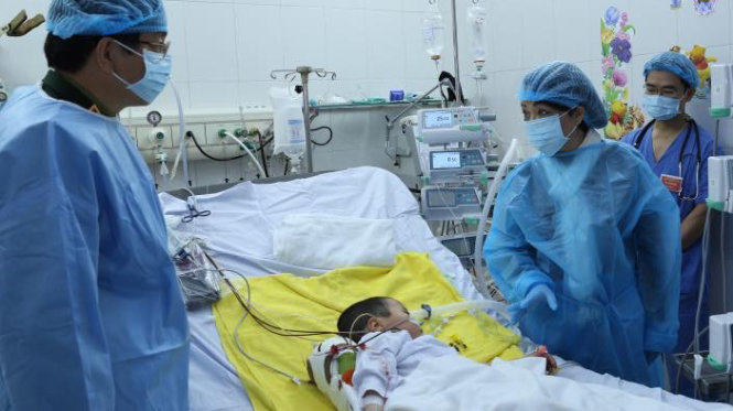 Bộ trưởng Bộ Y tế Nguyễn Thị Kim Tiến (bên phải giường bệnh) cùng thành viên ê kíp ghép phổi thăm bé Ly Chương Bình hôm 24-2 - Ảnh: Trần Ngọc Kha