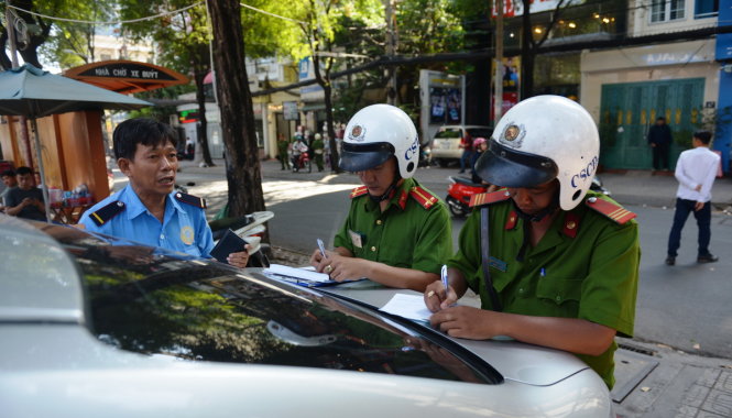 Cảnh sát trật tự quận 3 lập biên bản xử phạt xe ôtô đậu trên vỉa hè - Ảnh: Lê Phan