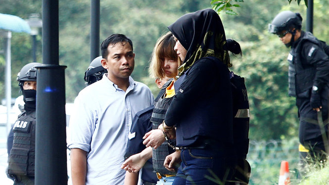 Cảnh sát dẫn giải Đoàn Thị Hương (giữa) sau phiên công bố cáo trạng tại Malaysia - Ảnh: Reuters