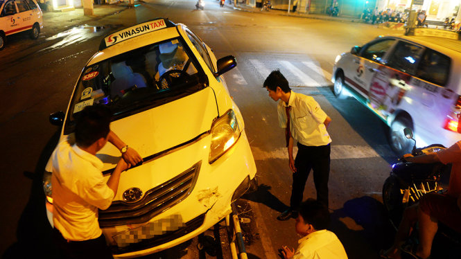 Nhiều tài xế taxi đã dừng xe xuống phụ đầy chiếc taxi bị nạn ra khỏi dải phân cách - Ảnh: HỮU KHOA