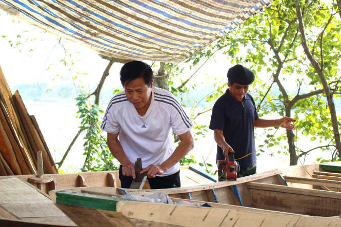 Ông Lê Văn Sơn (trái) gắn bó với nghề đóng thuyền 38 năm. Ông cùng người dân thôn Bến Đền mở cơ sở sản xuất ngay tại nhà 
Ảnh: HÀ THANH