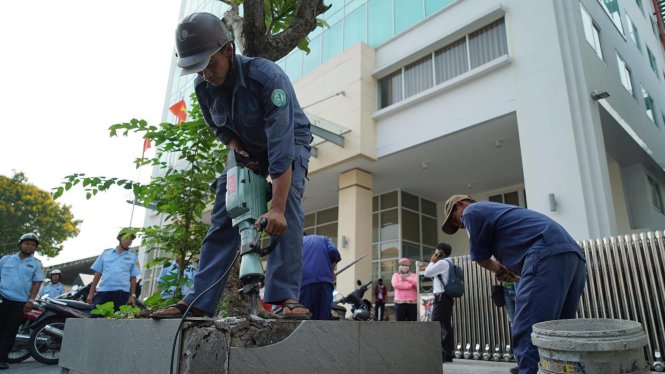 Đoàn kiểm tra đập bồn hoa lấn vỉa hè trước tòa nhà Bộ Công thương - Ảnh: THUẬN THẮNG