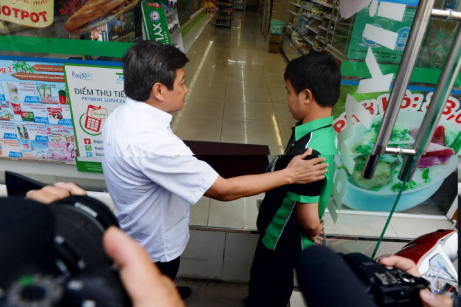 Ông Đoàn Ngọc Hải làm việc với nhân viên một cửa hàng tiện ích - nơi có phần cầu dẫn lấn chiếm vỉa hè trên đường Nguyễn Bỉnh Khiêm - Ảnh: Lê Phan