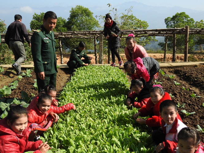 Trung tá Mùa A Páo hướng dẫn các em học sinh làm “vườn rau bộ đội”  Ảnh Việt Hùng