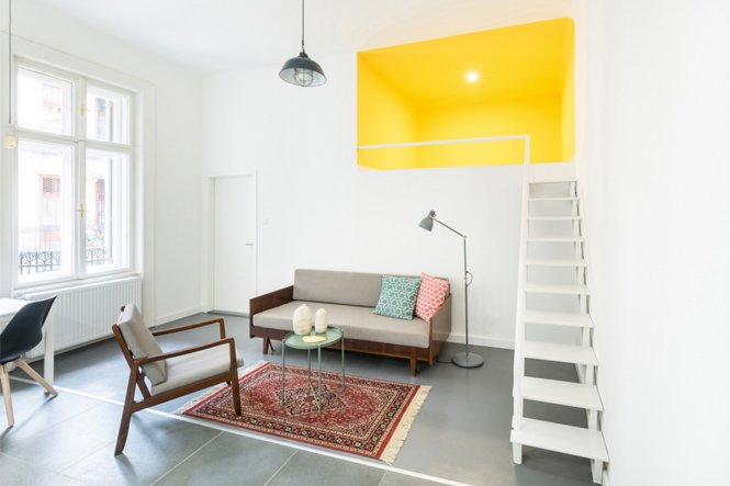 Phòng khách của căn hộ thứ hai nối liền với phòng làm việc nhỏ màu vàng tươi trên gác lửng
