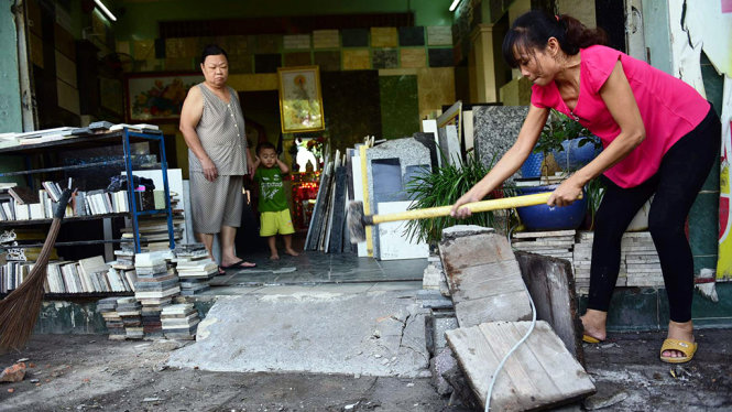 Người phụ nữ phụ lực lượng chức năng tháo dỡ bậc thềm lấn chiếm - Ảnh: Tâm Đức