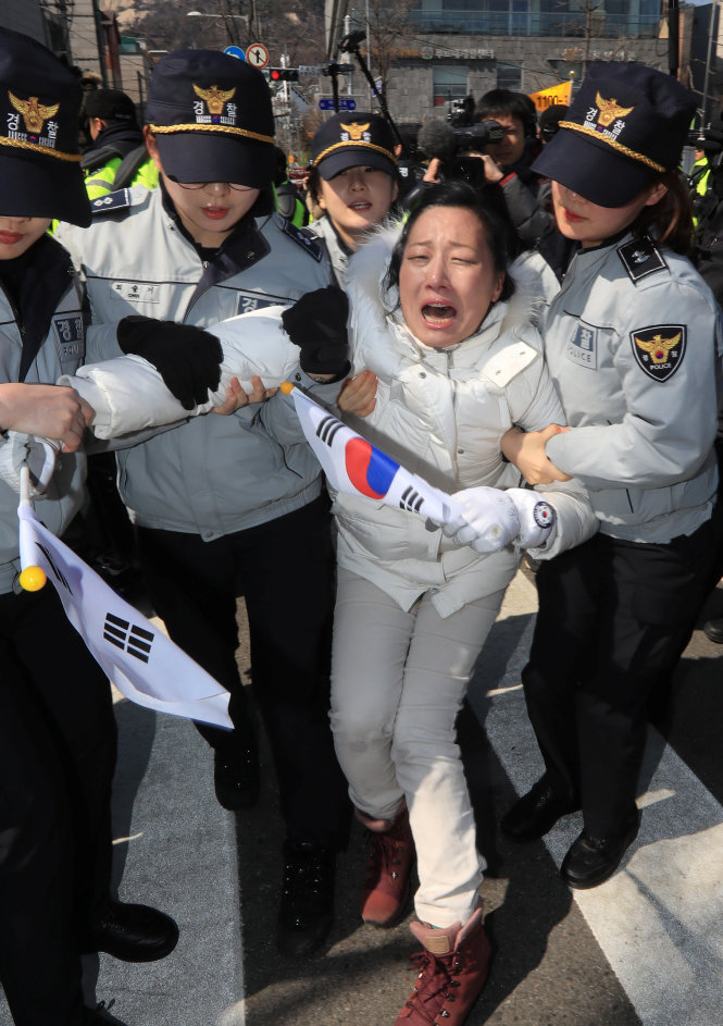 Cảnh sát Hàn Quốc dẫn giải một người dân ủng hộ bà Park trong lúc bà tỏ thái độ rất đau buồn sau quyết định của tòa - Ảnh: Reuters