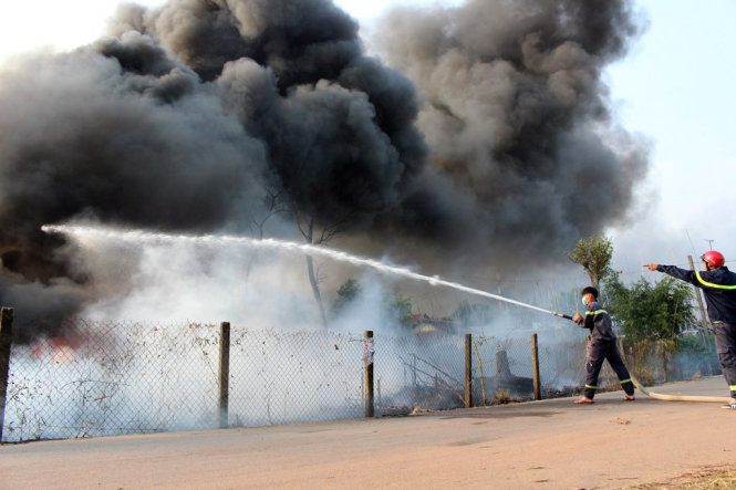 Lực lượng chữa cháy ngăn không cho ngọn lửa lan sang các hộ dân xung quanh - Ảnh: ĐÌNH TRỌNG