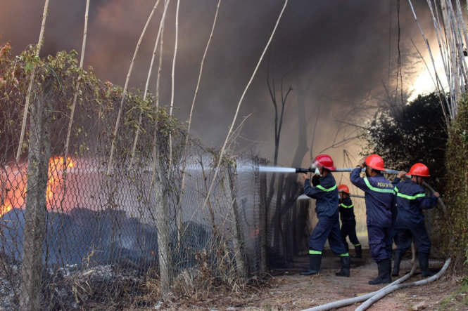 Lực lượng chữa cháy ngăn không cho ngọn lửa lan sang các hộ dân xung quanh - Ảnh: ĐÌNH TRỌNG