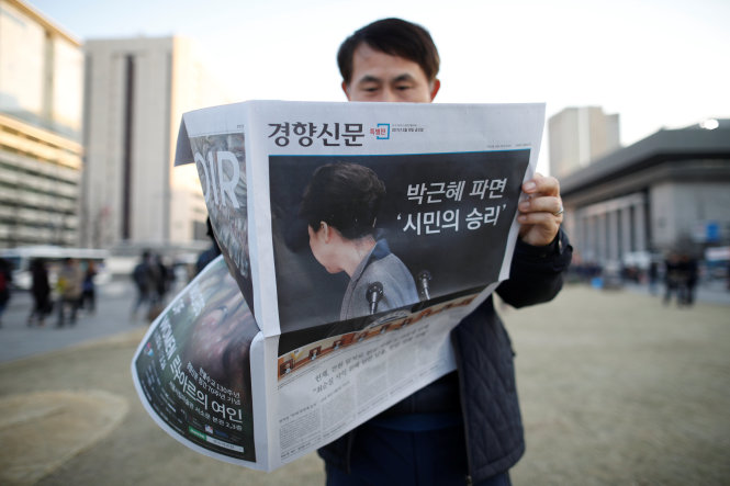 Một người đàn ông đang đọc báo trong lúc tham gia cuộc tuần hành kêu gọi bắt giữ bà Park tại trung tâm thủ đô Seoul - Ảnh: Reuters