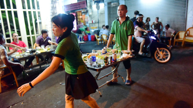 Nhân viên quán ăn  trên đường Cống Quỳnh, Q.1, TP.HCM  bê bàn  ăn vào khi thấy bóng dáng lực lượng trật tự đô thị của phường - Ảnh: HỮU THUẬN